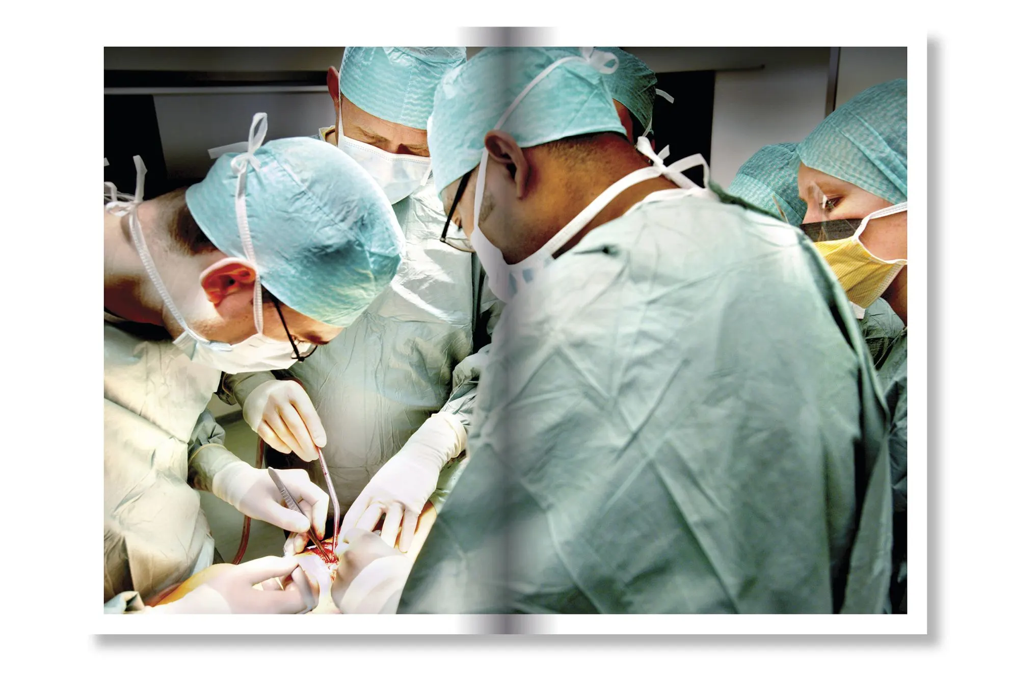 Surgeons in green gowns and caps operating on a patient, shown as a photo on a book page