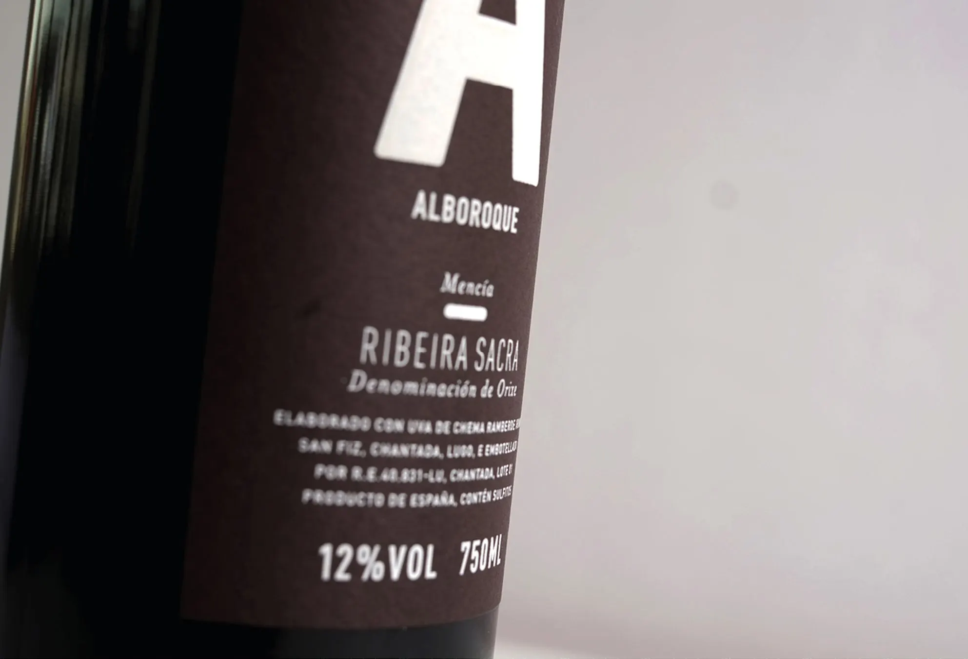 Close-up of the dark Alboroque wine label with a white horned 'A' emblem and 'Ribeira Sacra, 12% vol 750 ml'