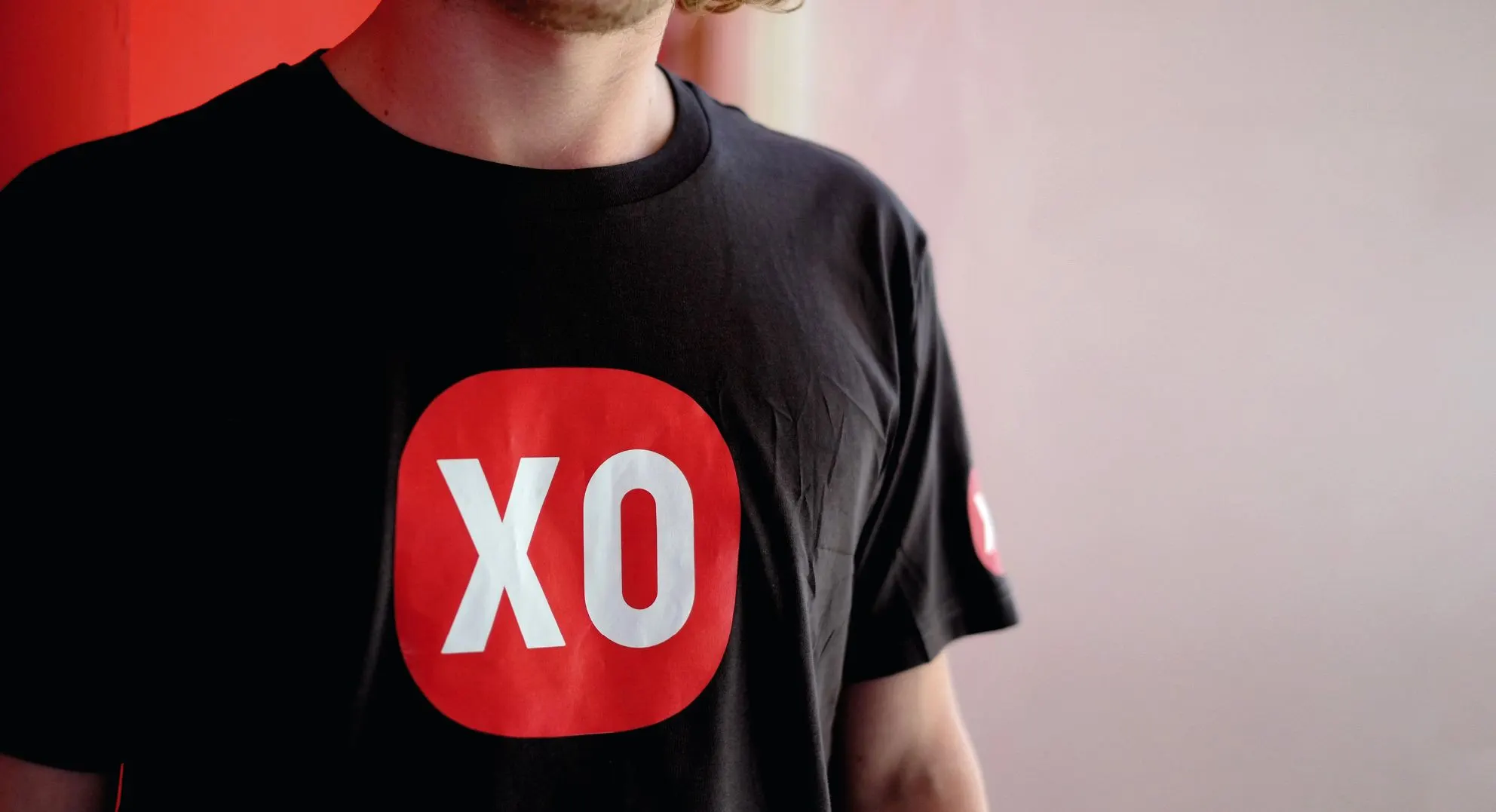 Person in a black T-shirt with a large red XO logo on the chest