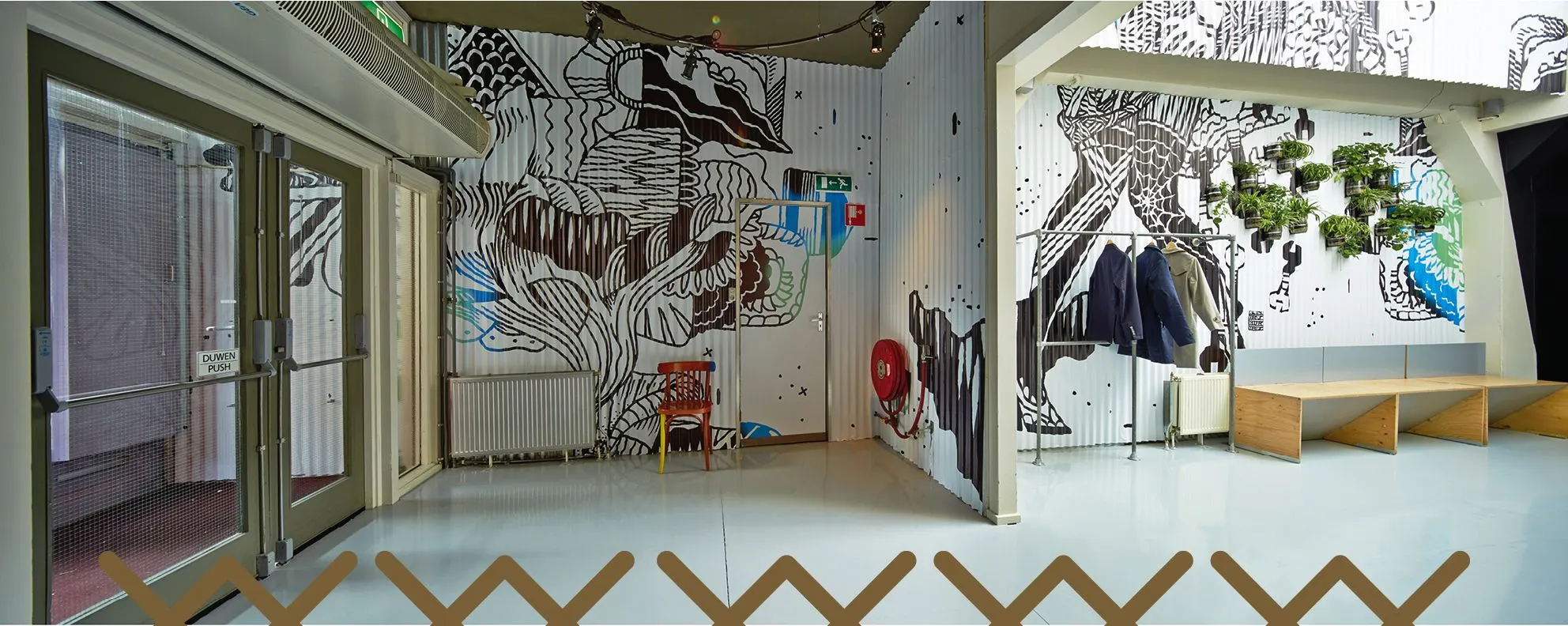 Ostade a'dam theatre foyer with black-and-white line-drawing murals and a golden cross pattern along the glass