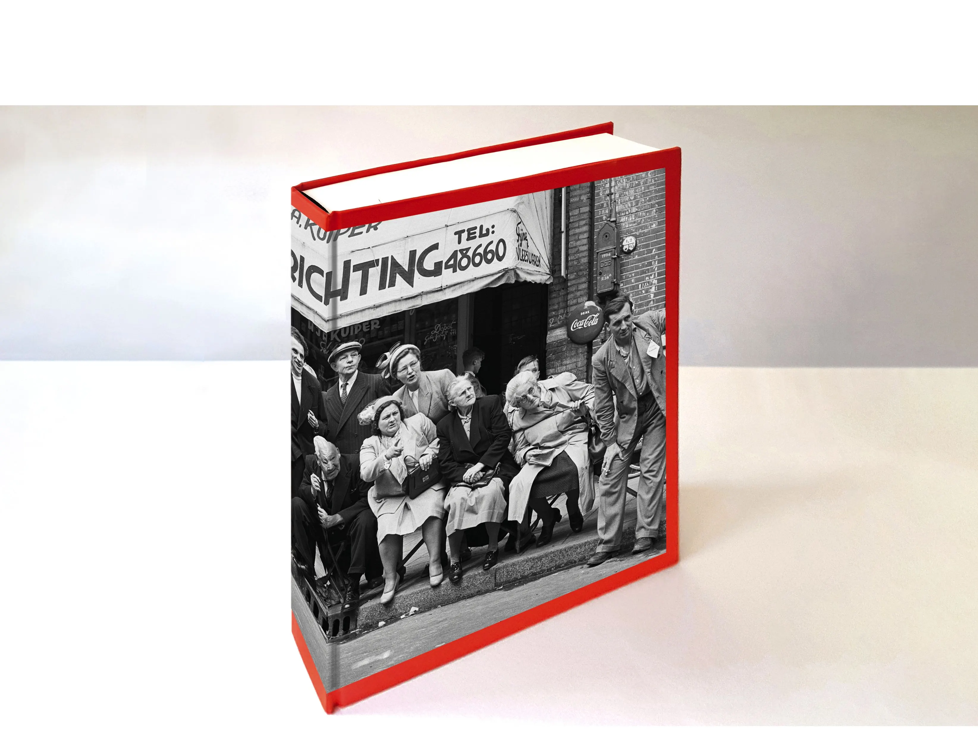 Thick hardcover book standing upright, red spine and a black-and-white cover photo of people outside a milk shop