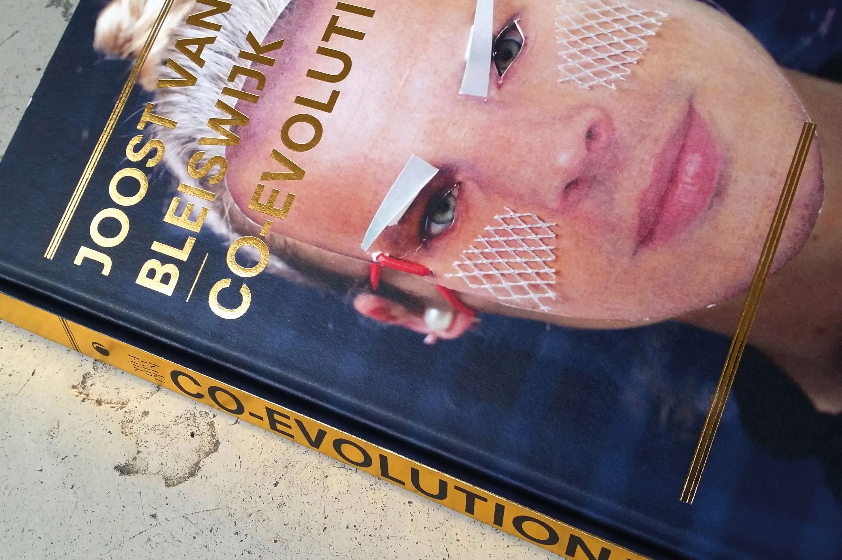 Cover of the Joost van Bleiswijk Co-evolution book with a face portrait and gold lettering