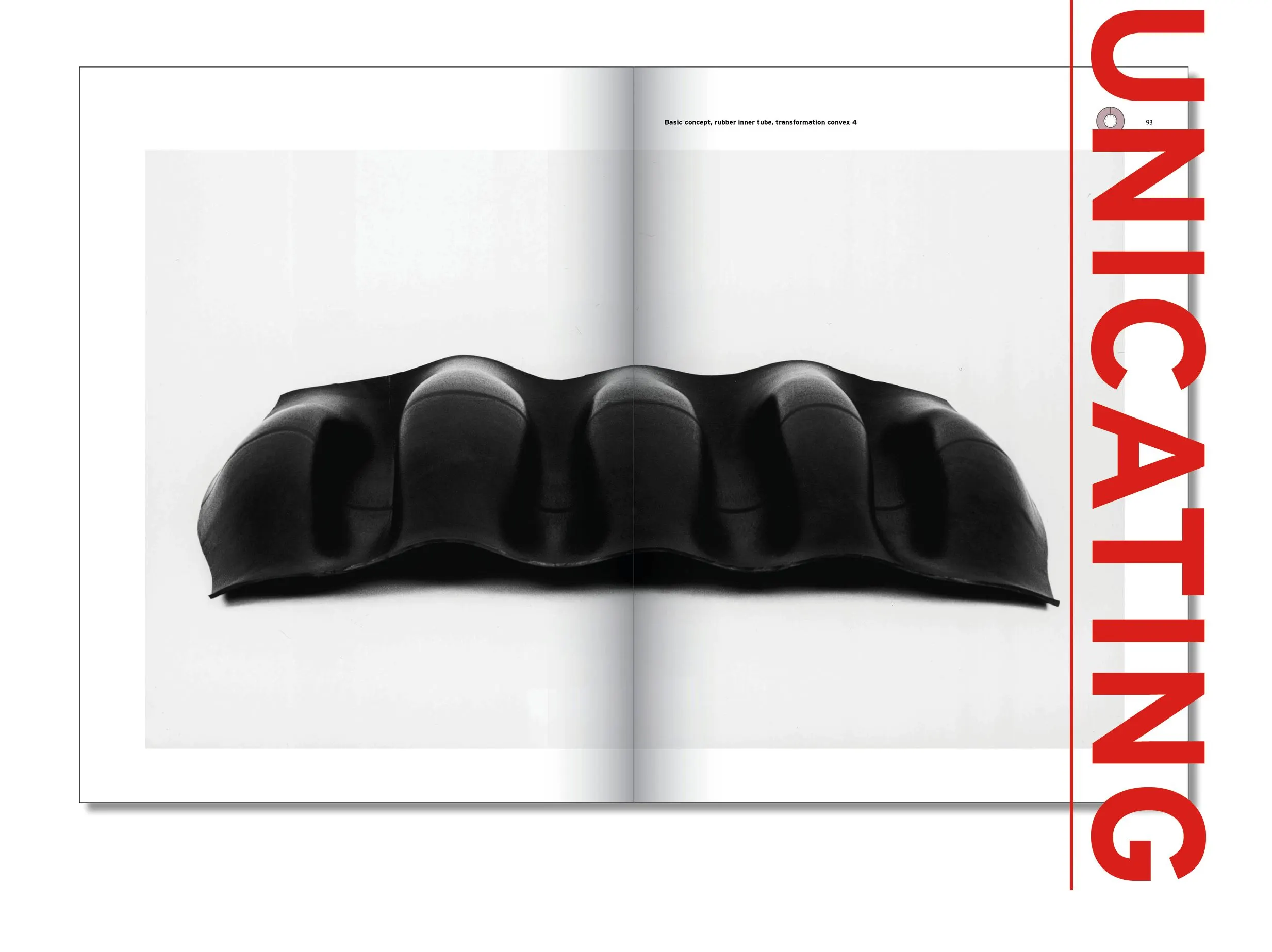 Book spread with a black inflatable sculpture with ridges on white and the red vertical word Communicating