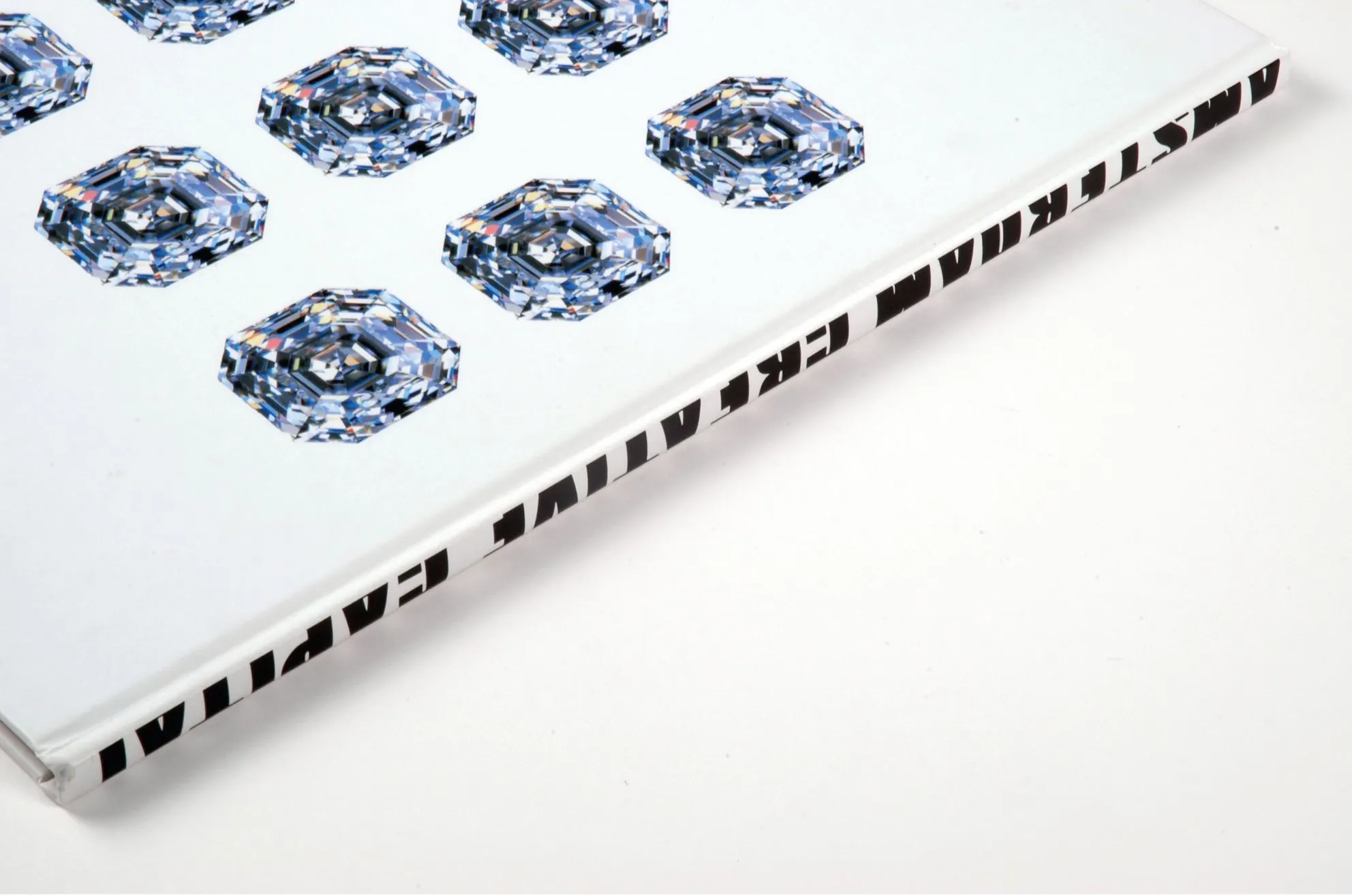 Book edge with black lettering beside a pattern of blue diamond illustrations on white