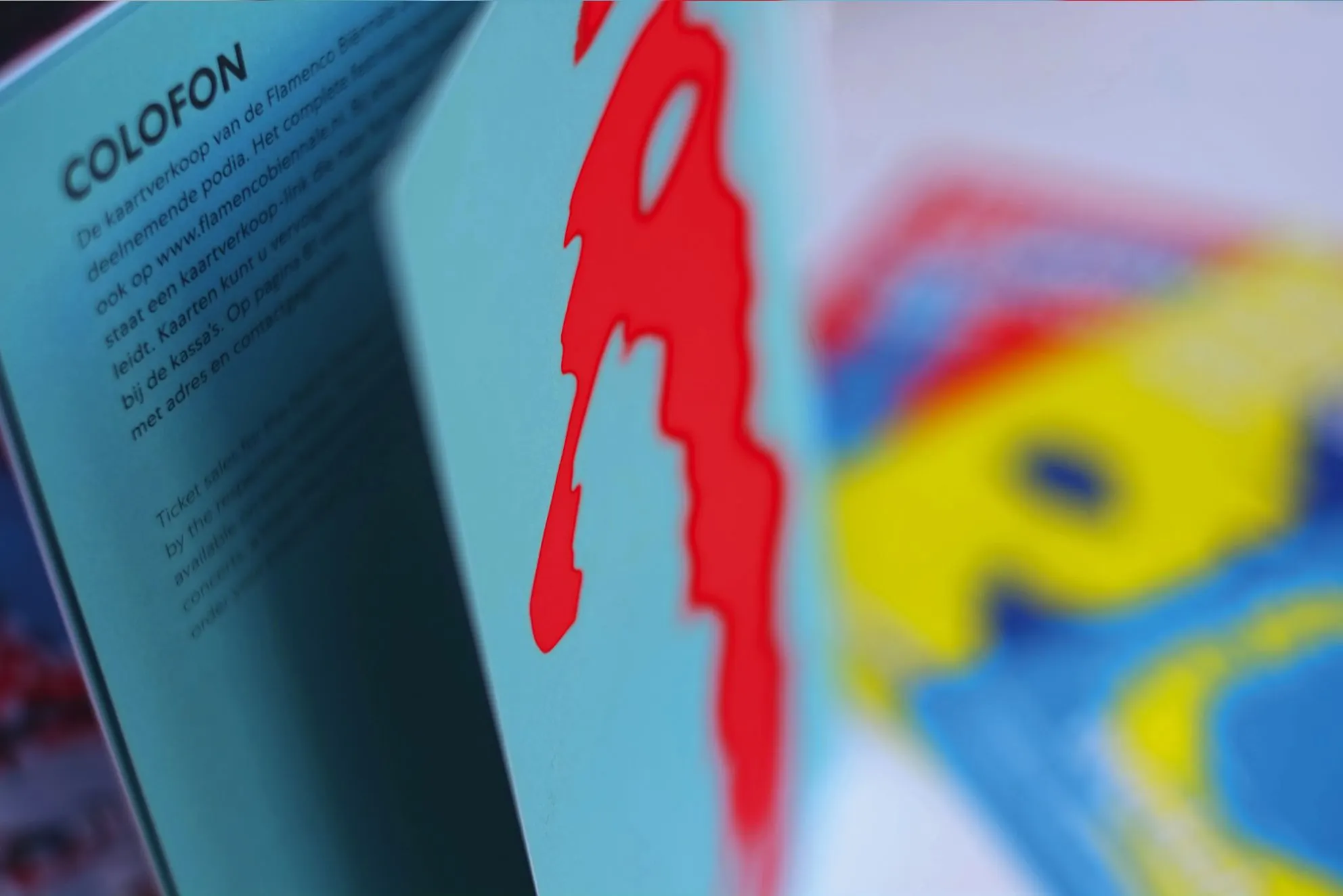 Close-up of a programme booklet colophon page with a red brushstroke on turquoise paper