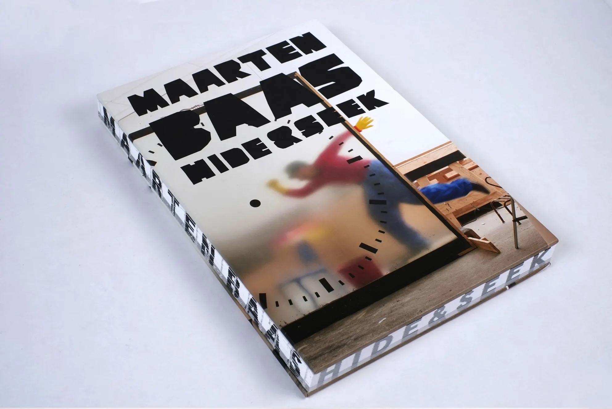 Book Maarten Baas Hide & Seek with a cover showing a blurred figure behind a frosted clock