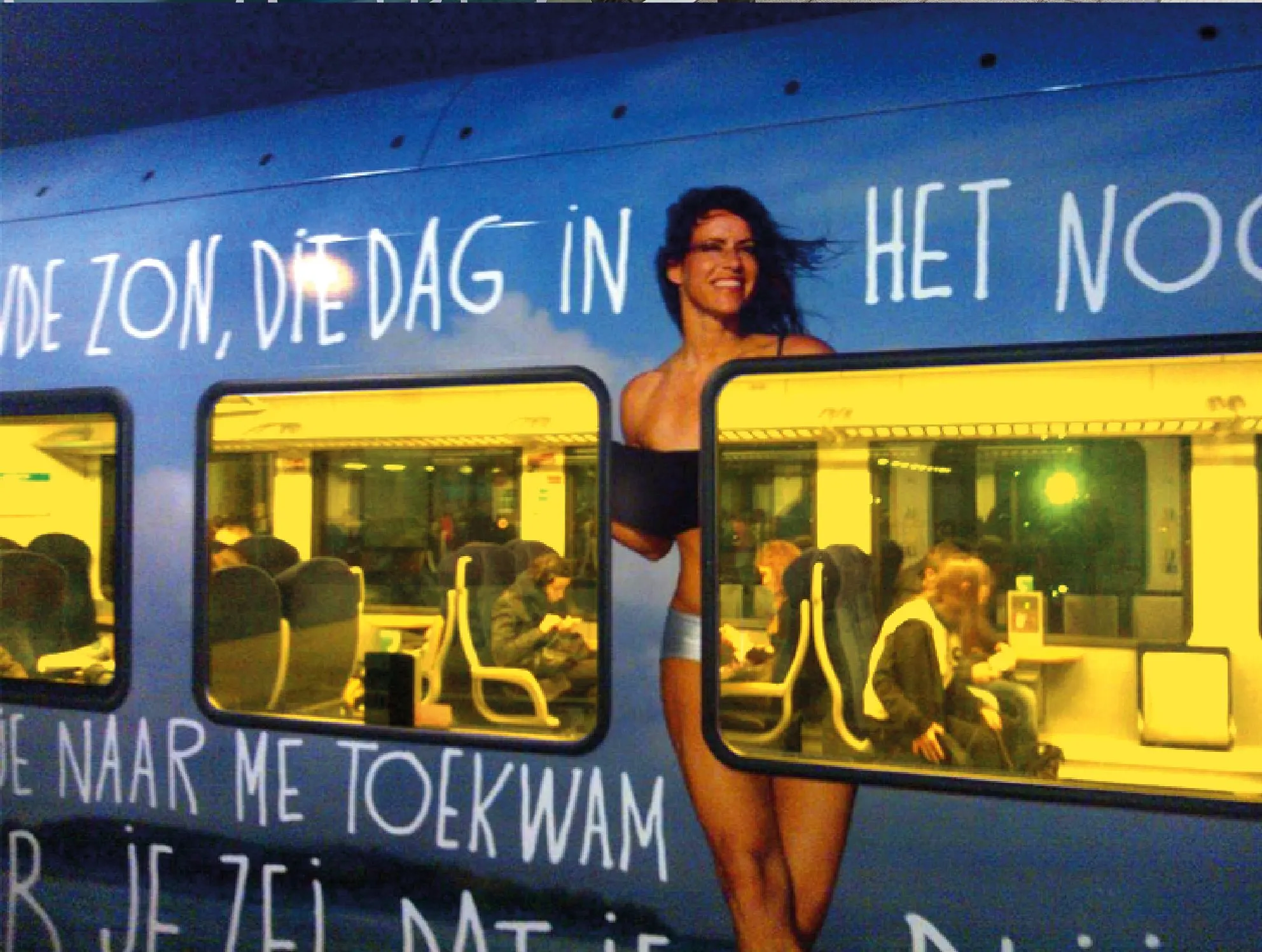 Close-up of the train at dusk with the artwork of a woman and lyrics across the carriage windows