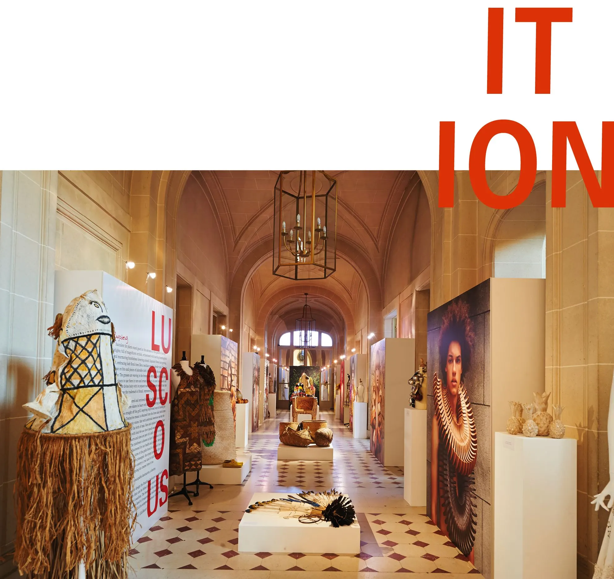 Exhibition hall with a gallery corridor and woven garments on display, with red letters LUSCIOUS and ITION