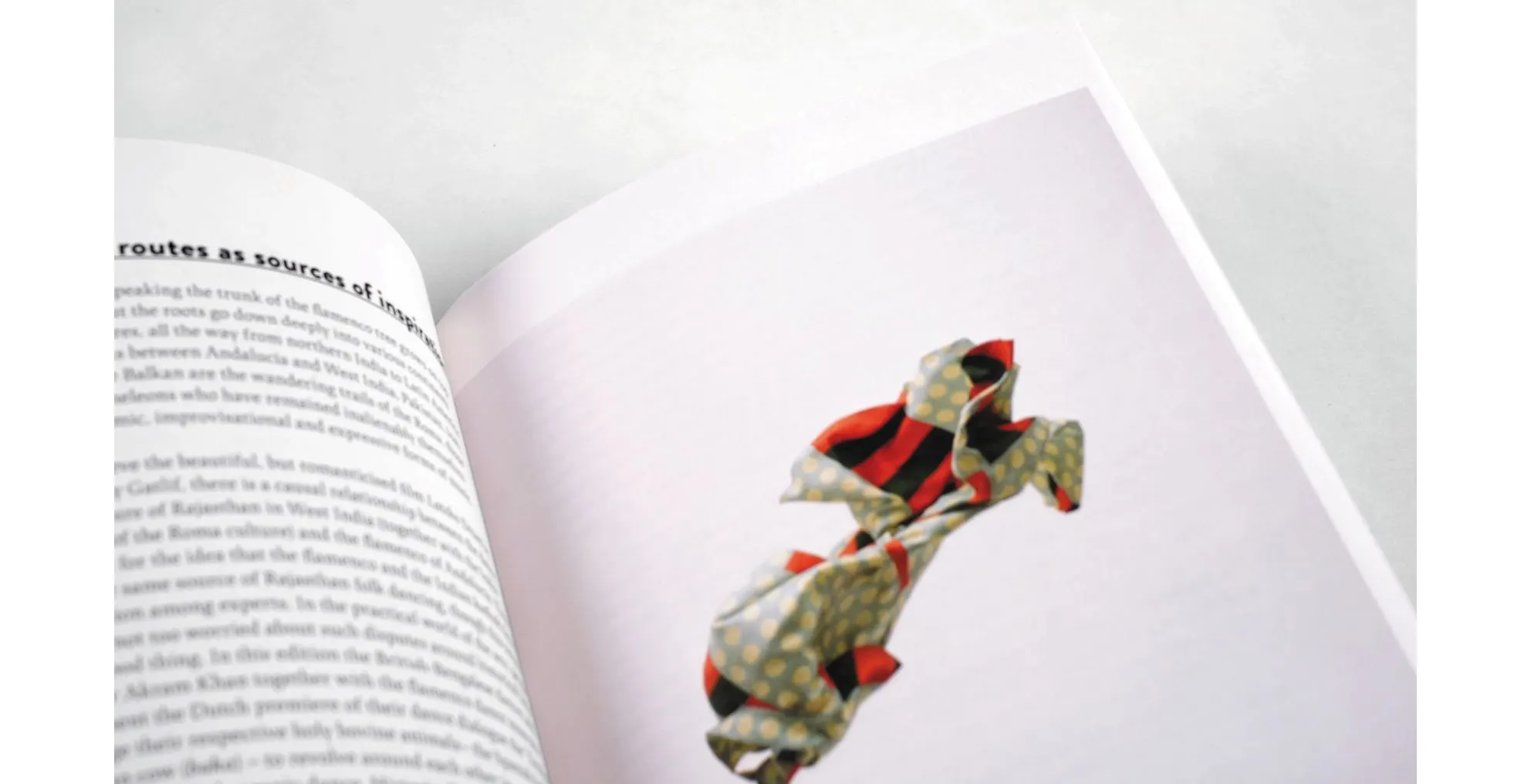 Book spread with dense text and a sculptural object made of red, black and patterned fabric